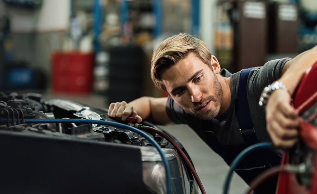 A technician working under the hood of a car